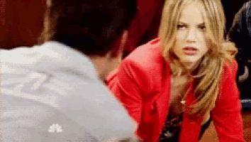 a woman in a red jacket is kneeling down in front of a man .