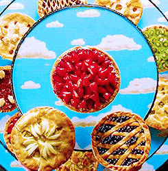 a variety of pies are on a blue plate with clouds in the background