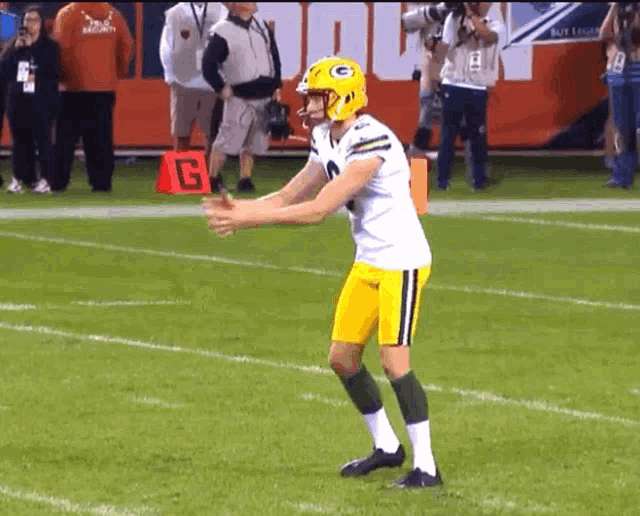 a football player wearing a green bay packers helmet stands on a field