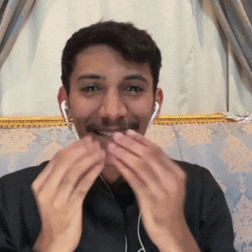 a man wearing ear buds is smiling and covering his mouth with his hands