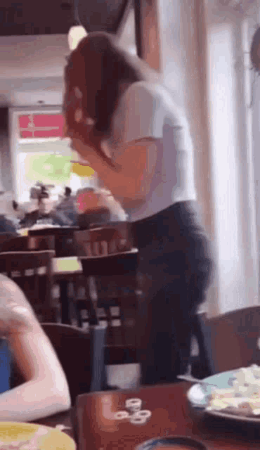 a woman sitting at a table in a restaurant with a plate of food on it