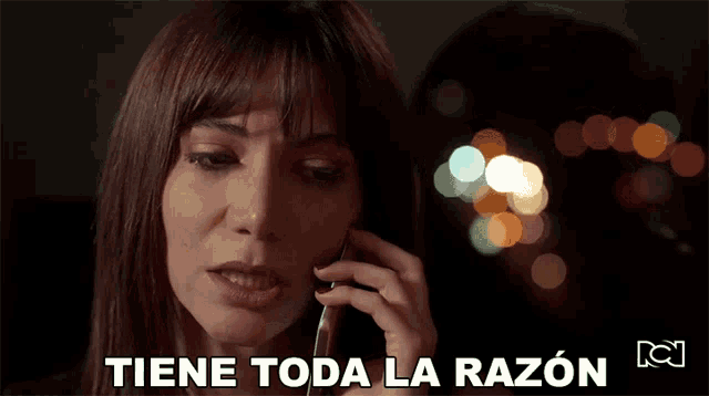 a woman is crying while talking on a cell phone and the words tiene toda la razon are below her