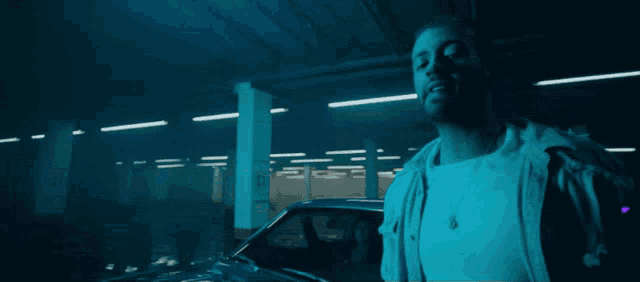 a man is standing in a dark parking garage with a purple arrow on his shoulder