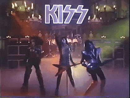 a kiss band is performing on a stage in front of a large sign