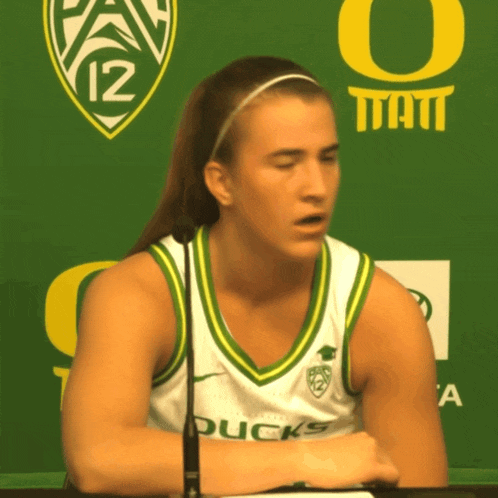 a woman wearing a ducks jersey sits at a desk