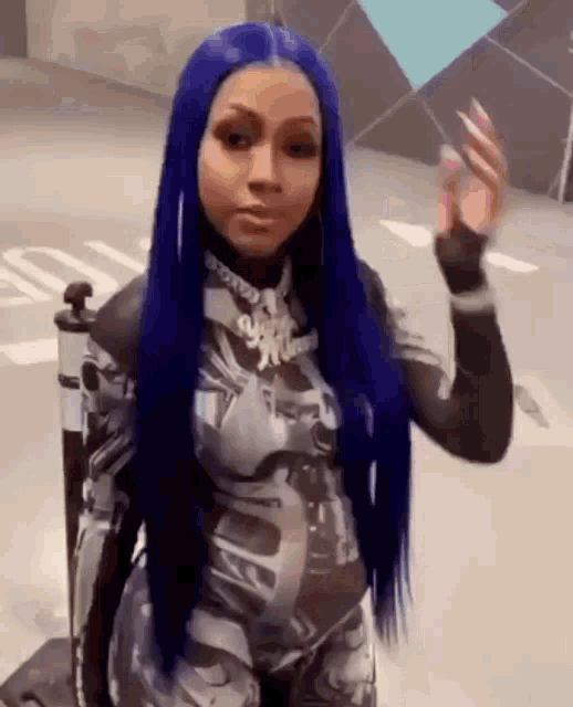 a woman with long blue hair is wearing a jumpsuit and waving at the camera .