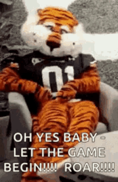 a tiger mascot is sitting in a chair and says `` oh yes baby let the game begin roar ! ''