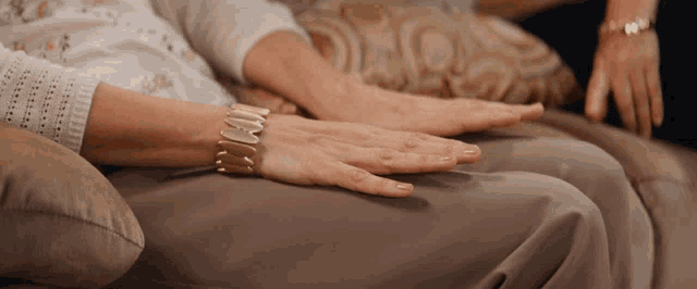 a woman wearing a bracelet on her wrist holds her hands together