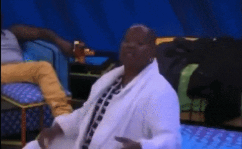 a man in a white robe is sitting on a couch with other people .
