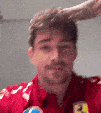 a man with a mustache is wearing a red ferrari shirt