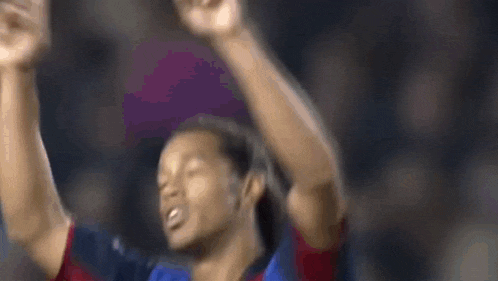 a soccer player is raising his arms in the air in a blurry photo .