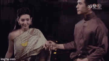 a man and a woman are holding hands and looking at each other in a dark room .