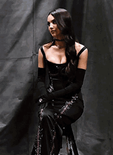 a woman in a black dress is sitting on a stool .
