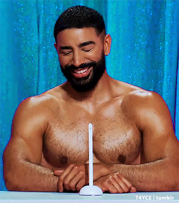 a shirtless man with a beard is sitting at a table with his eyes closed