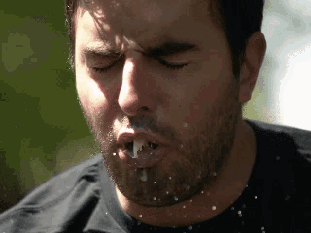 a close up of a man 's face with his eyes closed and a white substance coming out of his mouth