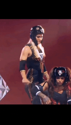 a woman in a wrestling outfit is standing next to a man in a boxing helmet on a stage .