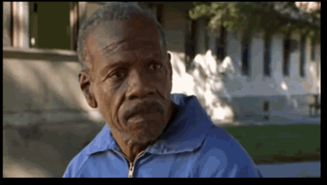 an elderly man in a blue jacket looks at the camera