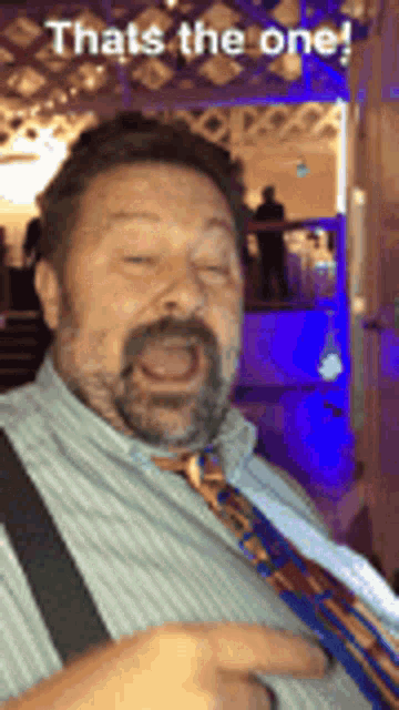 a man with a beard and suspenders is making a funny face while wearing a tie .