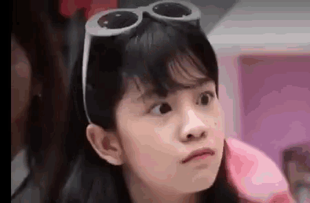 a little girl is wearing sunglasses and making a funny face .
