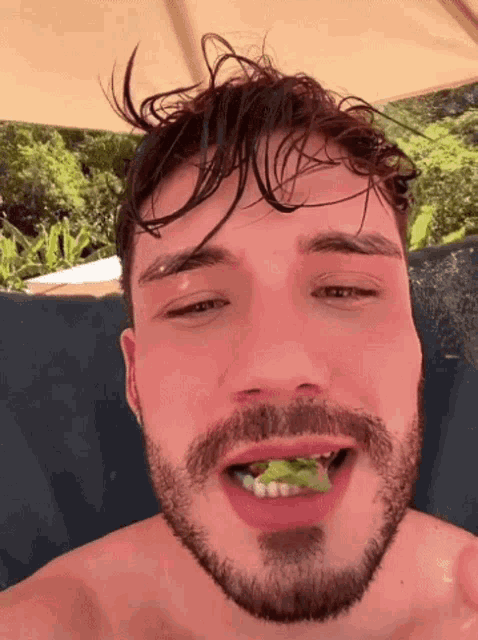 a man with a beard is eating a salad with his mouth open