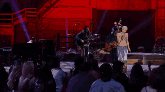 a man playing a guitar on a stage with a crowd watching