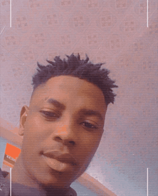a close up of a man 's face with a patterned wall behind him