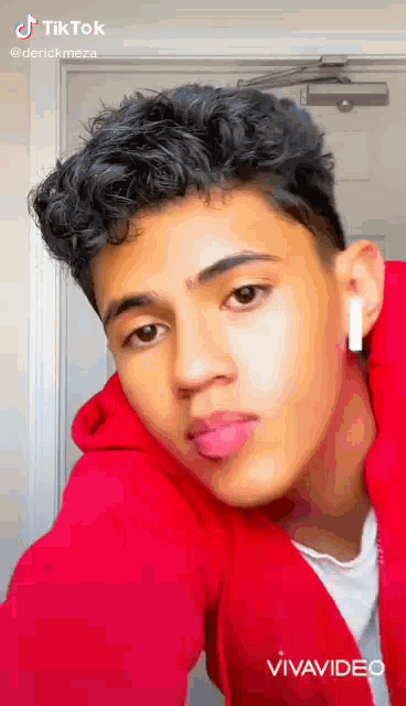 a young man is wearing a red hoodie and ear buds .