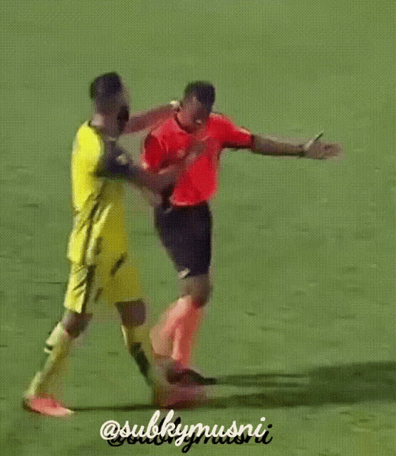 a soccer player in a yellow jersey is being tackled by a referee in a red shirt .
