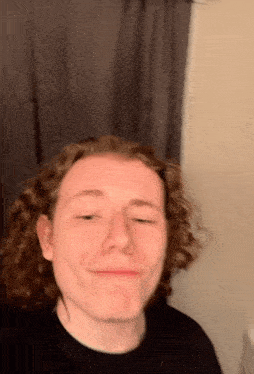 a young man with curly hair makes a funny face