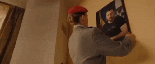 a woman in a military uniform is standing in front of a picture and says heil zelensky