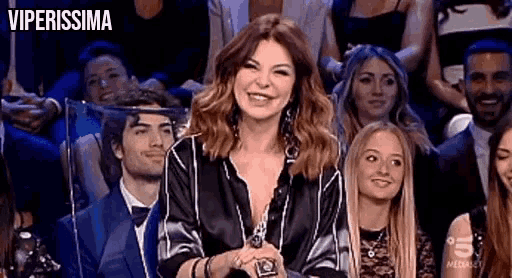 a woman is smiling in front of a crowd of people .