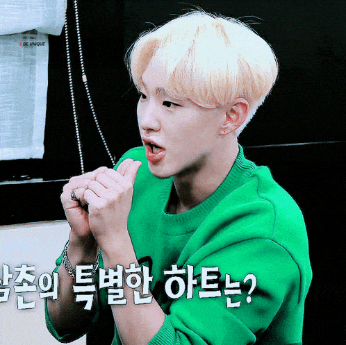 a young man wearing a green sweater with foreign writing on his arm