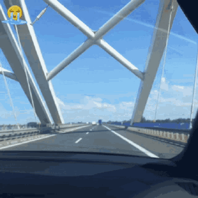 a car is driving across a bridge with a crying face sticker on the windshield