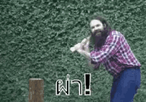a man with a beard is holding an axe in front of a hedge .