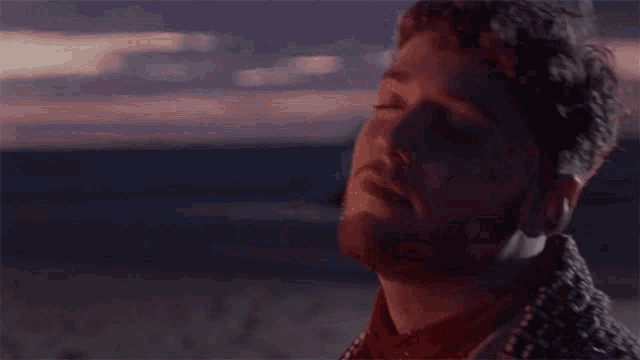 a man with a beard is looking at the sky with his eyes closed .