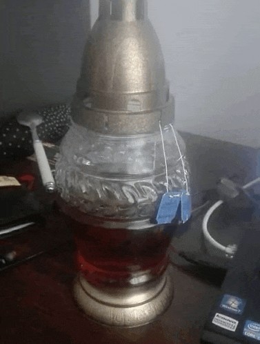 a candle with a tea bag in it sits on a table next to an intel laptop