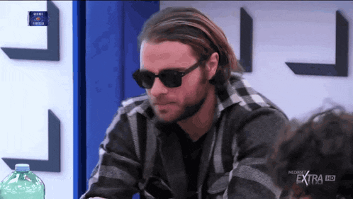 a man wearing sunglasses and a plaid shirt is on a tv screen that says extra hd
