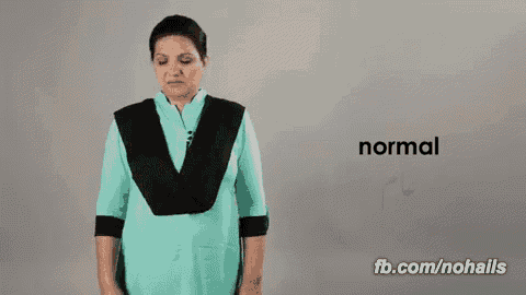 a woman in a blue shirt is standing in front of a wall that says normal