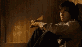 a man is sitting on the floor in front of a fireplace holding a bottle of alcohol .