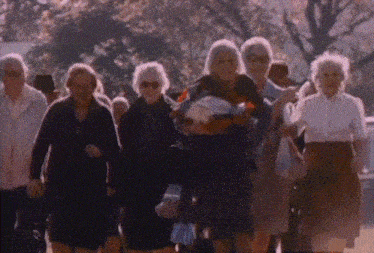 a group of elderly people are walking in a park