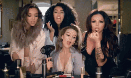 a group of women are standing around a table with cosmetics