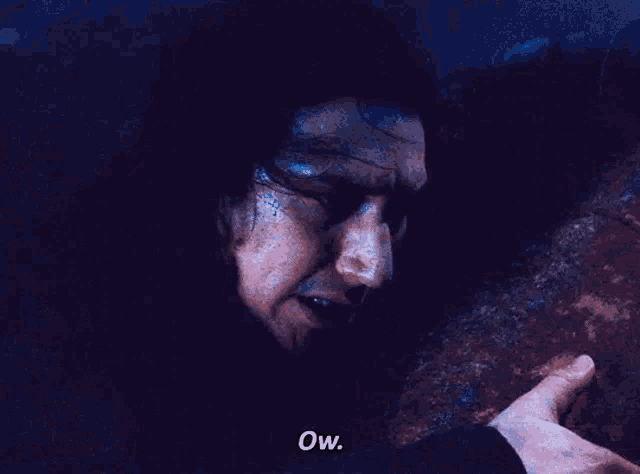 a close up of a man 's face with a hand reaching out towards it and the words ow .