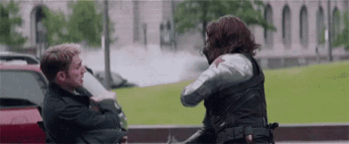 a man and a woman are standing next to each other on a sidewalk and fighting .