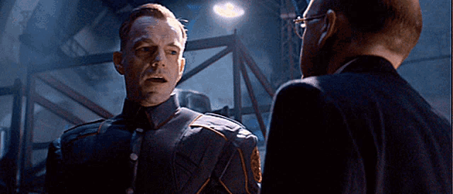a man in a military uniform talks to another man in a suit