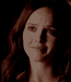 a close up of a woman 's face in a dark room with red hair .