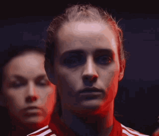 a close up of a woman 's face in a red and white adidas jersey .