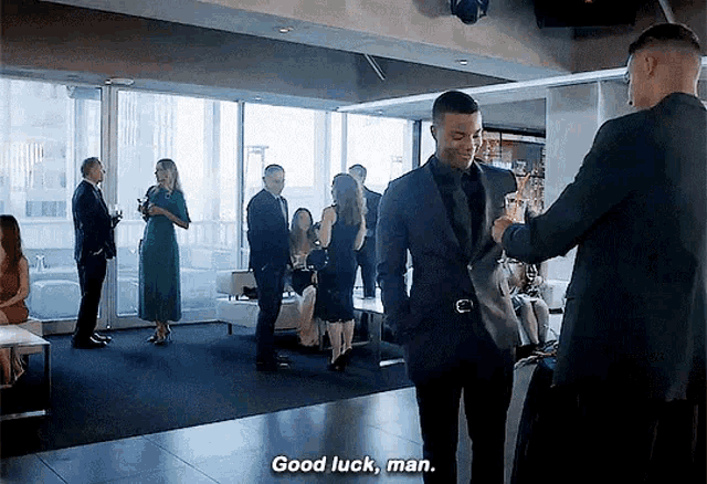 a man in a suit says good luck man while standing in a room