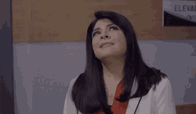 a woman in a lab coat is looking up at the sky in a hospital .