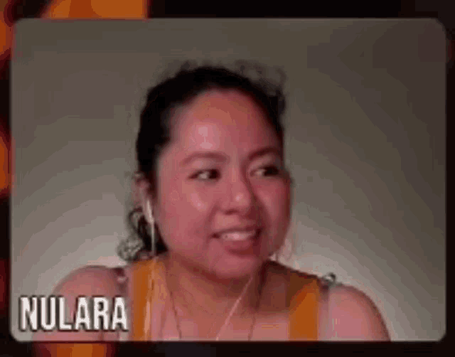 a woman wearing headphones and a yellow tank top is smiling and talking on a video call .