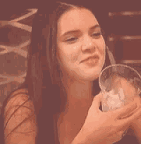 a woman is laughing while holding a glass of wine .